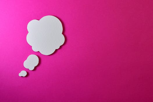 Paper thought bubble over bright pink background, ideal for creative concepts.