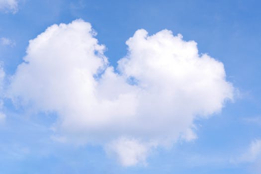 A fluffy, heart-shaped cloud set against a bright blue sky, symbolizing love and nature.